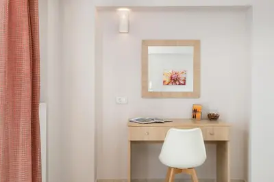 a desk with a white chair and a mirror at Mimosa in Maleme