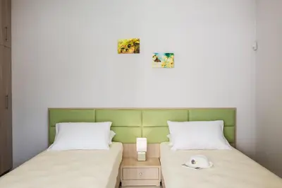 two twin beds in a small room with two pictures on the wall at Mimosa in Maleme