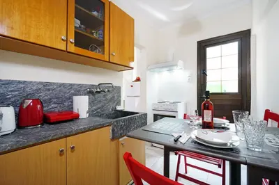 a kitchen with a table and red chairs in a kitchen at Nea Chora Maisonette in Chania Town