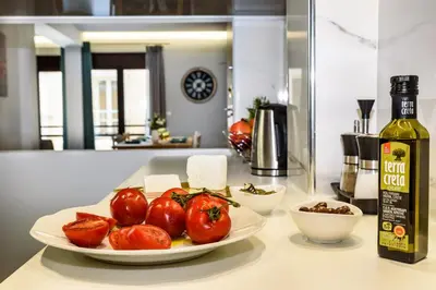 a plate of tomatoes on a counter with a bottle of wine at City Breeze Apartment in Chania Town
