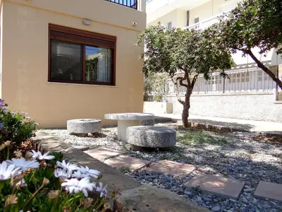 a garden with three stone benches in front of a building at Apartment by the Sea in Kato Daratso