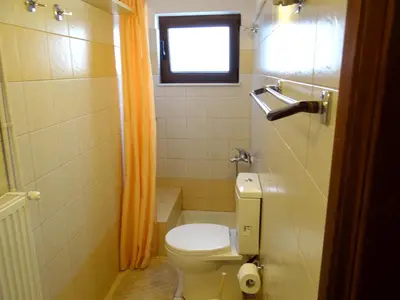 a bathroom with a toilet and an orange shower curtain at Apartment by the Sea in Kato Daratso