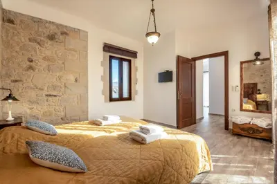 a bedroom with a bed and a stone wall at Villa Aerino in Azoyirás