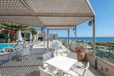a patio with tables and chairs and the ocean at Aphea Village in Kolymvari