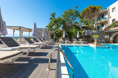 a pool at a hotel with lounge chairs and umbrellas at Aphea Village in Kolymvari