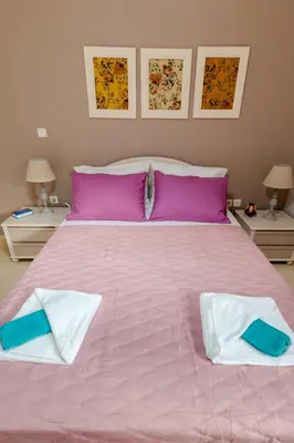 a large pink bed with two pillows on it at Skandalakis Homes & Apartments in Stalos