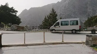 a white van driving down a road near a mountain at Neos Omalos Hotel in Omalós