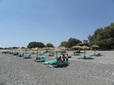 a group of people sitting on a beach with umbrellas at Megim Hotel in Palaiochóra