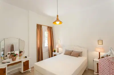 a white bedroom with a white bed and a mirror at Rena House in Kissamos