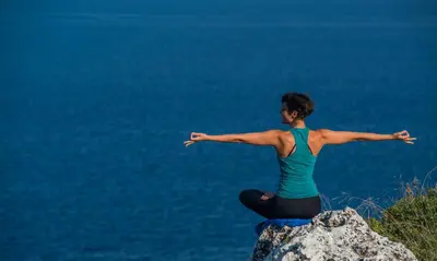 a woman sitting on top of a rock with her arms out at Olea Prime in Marathi