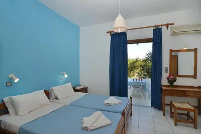 a bedroom with two beds and a mirror and a window at San Antonio Apartments in Kolymvari