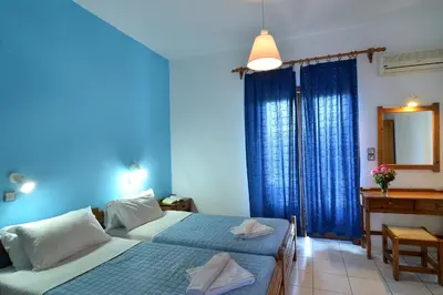 a bedroom with two beds and a desk and a mirror at San Antonio Apartments in Kolymvari