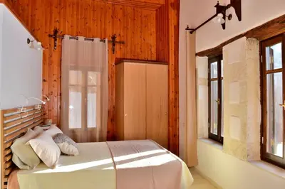a bedroom with a bed with a wooden wall at Charming stone corner house in Chania Town