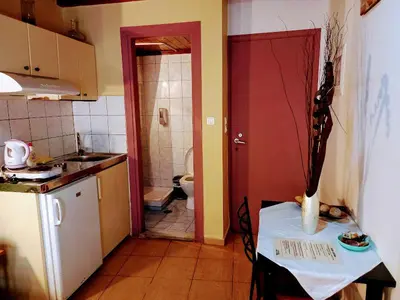 a kitchen with a table and a bathroom with a toilet at Caza Latina in Chania Town