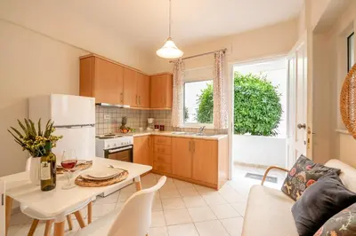 a kitchen and living room with a table and a white refrigerator at Sea Daffodil apartments in Kissamos
