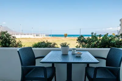 a table and chairs on a balcony with the beach at Sea Daffodil apartments in Kissamos