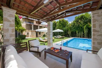 an outdoor patio with a white couch and a table next to a pool at Villa Arhontariki in Kissamos