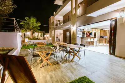 an outdoor patio with tables and chairs at night at Gregory Comfort Hotel in Kalamaki Chanion