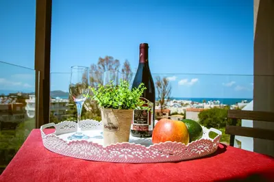 a table with a bottle of wine and fruit and a glass at Gregory Comfort Hotel in Kalamaki Chanion