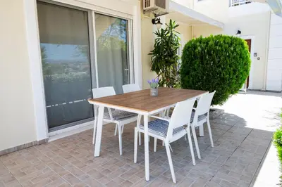 a wooden table and chairs on a patio at Barbaras Apartments in Kato Daratso