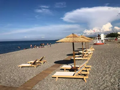 a group of lounge chairs and an umbrella on a beach at Angel-kolymvari4you in Kolymvari