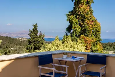 a table and two chairs on a balcony with trees at Heliopetra studios, small village close to beaches in Koprána