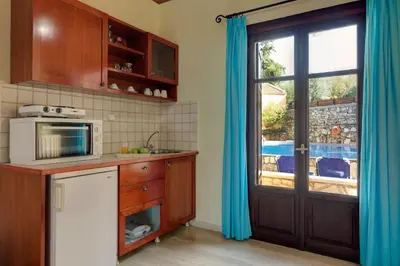 a kitchen with a sink and a microwave and a window at Heliopetra studios, small village close to beaches in Koprána