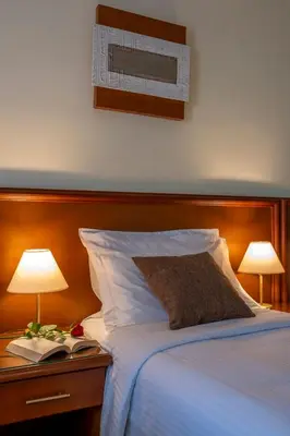a bedroom with a bed with two lamps and a book at Porto Alegre Hotel in Kalamaki Chanion
