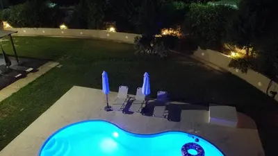 a swimming pool with chairs and umbrellas at night at Villa Leonton with a private pool in Kissamos
