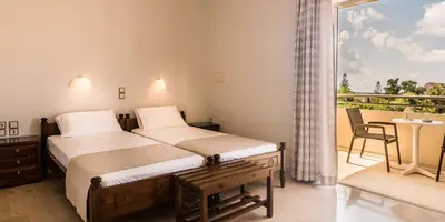 a hotel room with two beds and a balcony at Merabello Apartments in Agia Marina Nea Kydonias