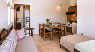 a living room with a dining room table and a kitchen at Merabello Apartments in Agia Marina Nea Kydonias