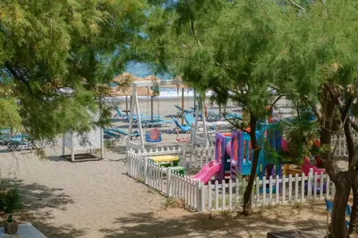 a playground with a white fence and play equipment at Seafront Paradise steps to Beach in Plataniás