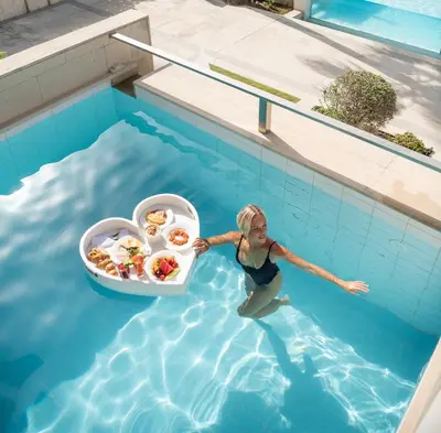 a woman in a swimming pool with a tray of food at Avra Imperial Hotel in Kolymvari