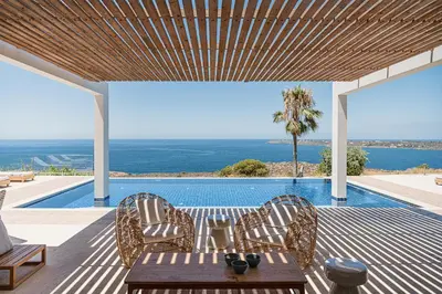 a patio with a table and chairs next to a swimming pool at Villa Jamila by Cura Villas Collection in Kalathas