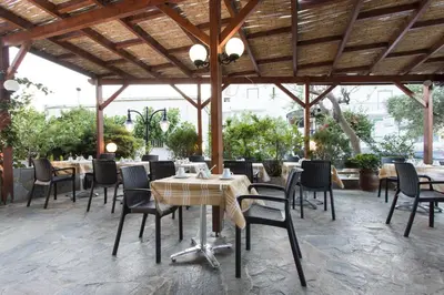 a restaurant with tables and chairs under a wooden roof at Glaros Hotel in Palaiochóra