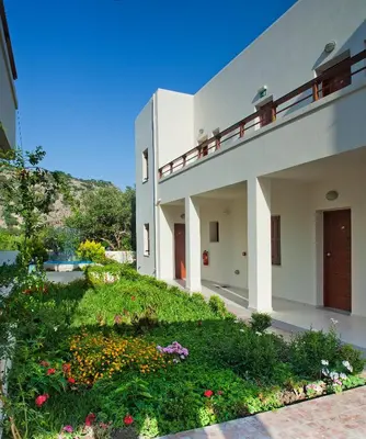 a large white building with a yard with flowers at Syia Hotel in Sougia