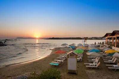 a group of chairs and umbrellas on a beach at sunset at Seafalios in Kalamaki Chanion