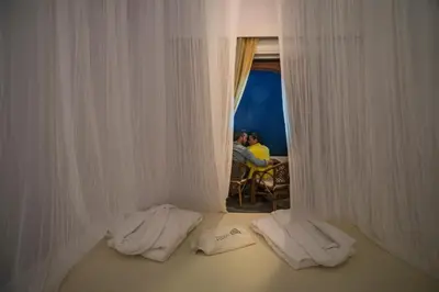 a room with white curtains and two people sitting at a table at Villa Georgia Apartments & Suites in Kalamaki Chanion