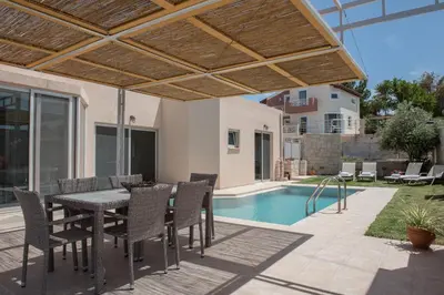 a patio with a table and chairs and a swimming pool at Pantanassa Villa Thalia in Agia Marina Nea Kydonias