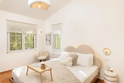 a white bedroom with a large bed and a table at Seaview Garden Villa - Heated Pool & Sauna in Stalos