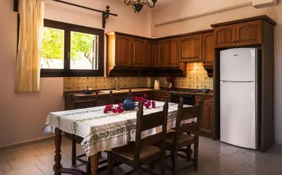 a kitchen with a table with chairs and a refrigerator at Villa Merabello in Agia Marina Nea Kydonias