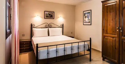 a bedroom with a bed and a wooden cabinet at Villa Merabello in Agia Marina Nea Kydonias