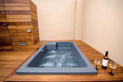 a hot tub in a room with two glasses of wine at Portou House in Chania Town