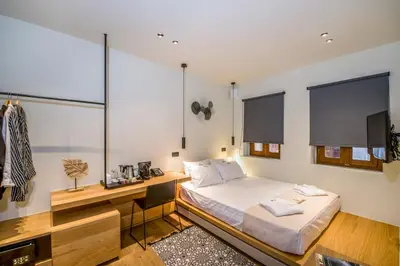 a bedroom with a bed and a desk and windows at Portou House in Chania Town