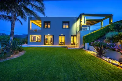 a large house with a green yard at night at Mythic Olive villa - Heated Pool - Amazing view in Perivólia