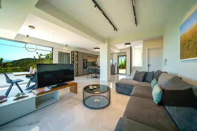 a living room with a couch and a television at Mythic Olive villa - Heated Pool - Amazing view in Perivólia
