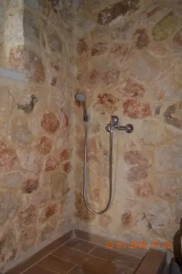 a shower in a bathroom with a stone wall at Rumpis Traditional House in Kambánion