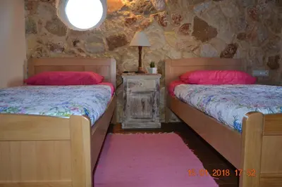 a bedroom with two beds and a stone wall at Rumpis Traditional House in Kambánion