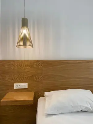 a bedroom with a bed with a wooden headboard and a lamp at Frini Hotel in Chania Town