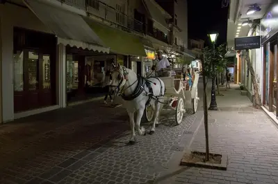 a man riding a horse drawn carriage down a street at Emmanouil’s House in Chania Town